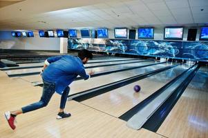 sfocatura foto dell'uomo del sud asiatico posteriore lancia palla da bowling in movimento al vicolo.