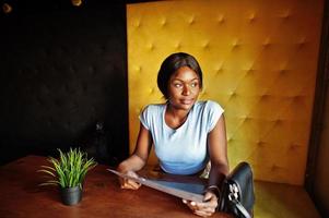 ragazza afroamericana seduta al bar con menu a portata di mano. donna nera che riposa. foto