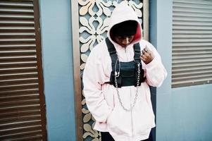 elegante uomo afroamericano in stile urbano in felpa con cappuccio rosa in posa. ragazzo afro rapper. foto