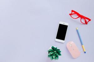 scrivania creativa in stile piatto con smartphone, cancelleria, mouse e occhiali su sfondo colorato con spazio per la copia foto