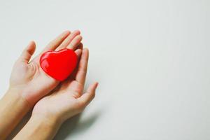 una donna che mette un cuore rosso sul palmo della mano con uno sfondo bianco. idea di donazione foto