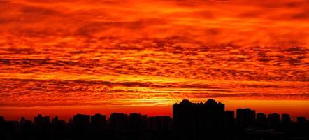 il profilo nero della città di notte sullo sfondo di un'alba sanguinosa al mattino presto. foto
