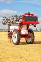 atomizzatore trainato agricolo per colture di campo guida in uno stato di trasporto piegato sullo sfondo di un campo di grano raccolto. foto