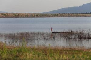 sagoma di pescatore sulla barca di legno al lago. foto