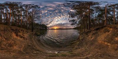 panorama hdri sferico completo senza soluzione di continuità vista a 360 gradi sulla costa di un enorme fiume o lago nella foresta di pini con fantastiche nuvole prima del tramonto in proiezione equirettangolare, pronto per contenuti vr ar foto