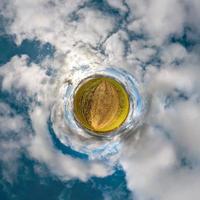 trasformazione del piccolo pianeta del panorama sferico a 360 gradi. vista aerea astratta sferica in campo con bellissime nuvole fantastiche. curvatura dello spazio. foto