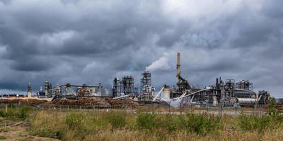 tubi della segheria della pianta di impresa di lavorazione del legno contro un cielo grigio cupo. concetto di inquinamento atmosferico. panorama del paesaggio industriale inquinamento ambientale rifiuti di centrale termica foto