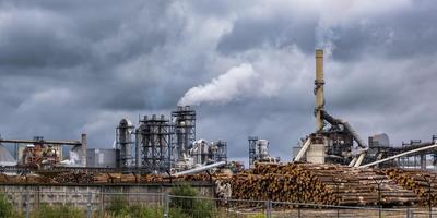 tubi della segheria della pianta di impresa di lavorazione del legno contro un cielo grigio cupo. concetto di inquinamento atmosferico. panorama del paesaggio industriale inquinamento ambientale rifiuti di centrale termica foto