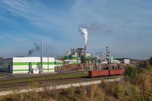 tubi della segheria dell'impianto di impresa di lavorazione del legno vicino al fiume. concetto di inquinamento atmosferico. paesaggio industriale inquinamento ambientale rifiuti di centrale termica foto