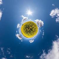 trasformazione del piccolo pianeta del panorama sferico a 360 gradi. vista aerea astratta sferica nel campo di colza con bellissime nuvole fantastiche. curvatura dello spazio. foto