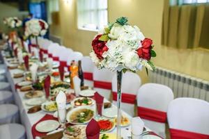 vista del servito per la tavola da pranzo di nozze decorata in un ristorante d'élite con bellissimi fiori. foto