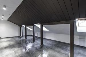 Loft vuoto non arredato mansarda interna con colonne in legno e pavimento in cemento bagnato a livello del tetto in colore nero e bianco foto
