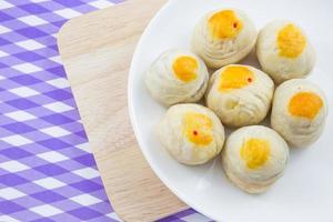 fagiolo cinese della pasticceria o mooncake con tuorlo d'uovo sul piatto e panno a strisce della tavola di legno foto