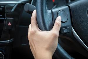 una mano di donna spinge il pulsante di controllo del volume su un volante. foto