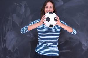 donna che tiene un pallone da calcio davanti al tavolo da disegno di gesso foto