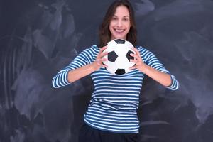 donna che tiene un pallone da calcio davanti al tavolo da disegno di gesso foto