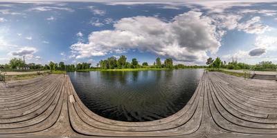 panorama hdri sferico completo senza cuciture vista angolare a 360 gradi sul molo in legno del lago o del fiume con bellissime nuvole in proiezione equirettangolare, contenuto vr foto