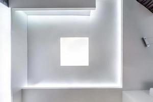 guardando in alto sul soffitto sospeso con lampade alogene e costruzione di cartongesso in una stanza vuota in appartamento o casa. soffitto teso bianco e di forma complessa. foto