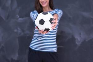 donna che tiene un pallone da calcio davanti al tavolo da disegno di gesso foto