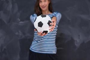 donna che tiene un pallone da calcio davanti al tavolo da disegno di gesso foto