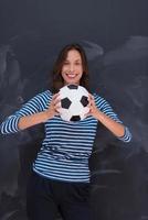 donna che tiene un pallone da calcio davanti al tavolo da disegno di gesso foto