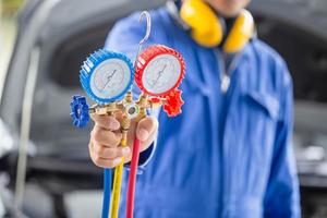 strumento di monitoraggio della tenuta del riparatore per controllare e riparare il sistema del condizionatore d'aria dell'auto, il tecnico controlla la ricarica del refrigerante del sistema di aria condizionata dell'auto, riparazione dell'aria condizionata foto