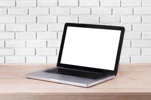 la vista frontale del laptop è sul tavolo da lavoro e sullo sfondo di mattoni bianchi foto
