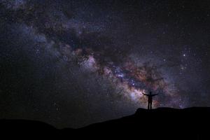 paesaggio con via lattea, cielo notturno con stelle e silhouette di persone felici in piedi sulla montagna, fotografia a lunga esposizione, con grano foto