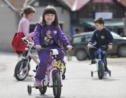 gruppo di bambini felici che imparano a guidare la bicicletta foto