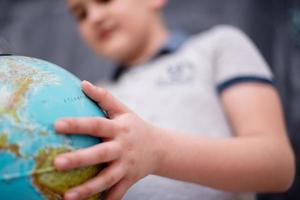 ragazzo che usa il globo terrestre davanti alla lavagna foto