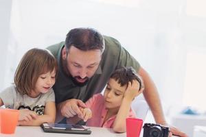 padre single a casa con due bambini che giocano sul tablet foto