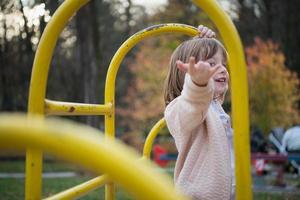 bambina sveglia che si diverte nel parco giochi foto