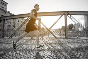 uomo che fa jogging attraverso il ponte al mattino soleggiato foto