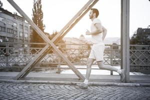 uomo che fa jogging attraverso il ponte al mattino soleggiato foto