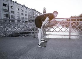 uomo che fa jogging attraverso il ponte al mattino soleggiato foto