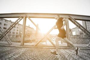 uomo che fa jogging attraverso il ponte al mattino soleggiato foto