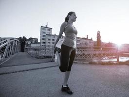 donna che fa jogging attraverso il ponte al mattino soleggiato foto