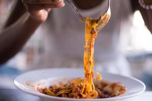 una giovane donna afroamericana che mangia pasta foto