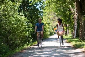 giovane coppia multietnica che fa un giro in bicicletta nella natura foto