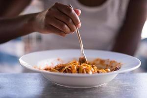 una giovane donna afroamericana che mangia pasta foto