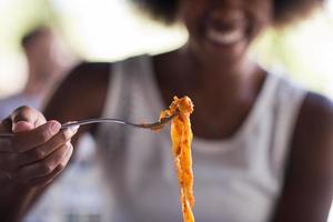 una giovane donna afroamericana che mangia pasta foto