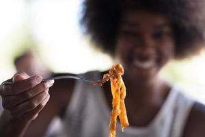 una giovane donna afroamericana che mangia pasta foto
