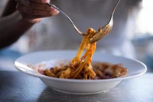 una giovane donna afroamericana che mangia pasta foto