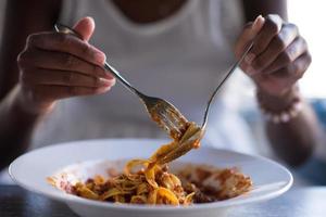 una giovane donna afroamericana che mangia pasta foto