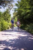 giovane coppia multietnica che fa un giro in bicicletta nella natura foto