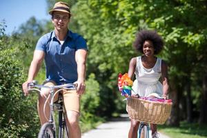 giovane coppia multietnica che fa un giro in bicicletta nella natura foto