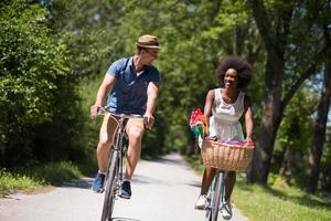 giovane coppia multietnica che fa un giro in bicicletta nella natura foto