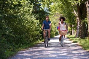 giovane coppia multietnica che fa un giro in bicicletta nella natura foto