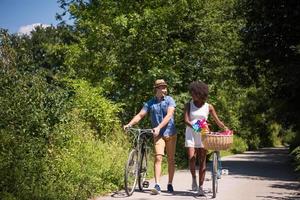 giovane coppia multietnica che fa un giro in bicicletta nella natura foto