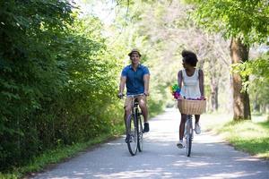 giovane coppia multietnica che fa un giro in bicicletta nella natura foto